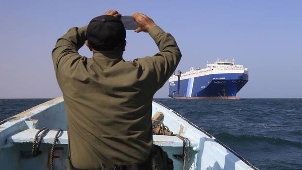 Ein Jemenit, der auf einem Boot sitzt, filmt mit einem Mobiltelefon das Frachtschiff Galaxy Leader, das von den Houthis vor dem Hafen von Al-Salif am Roten Meer in der Provinz Hodeidah, Jemen, am 19. November 2023 beschlagnahmt wurde.