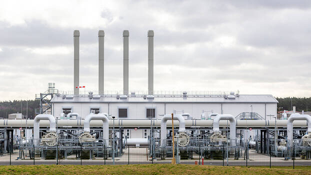 Fabrik mit vielen großen Rohrsystemen hinter einem Zaun.